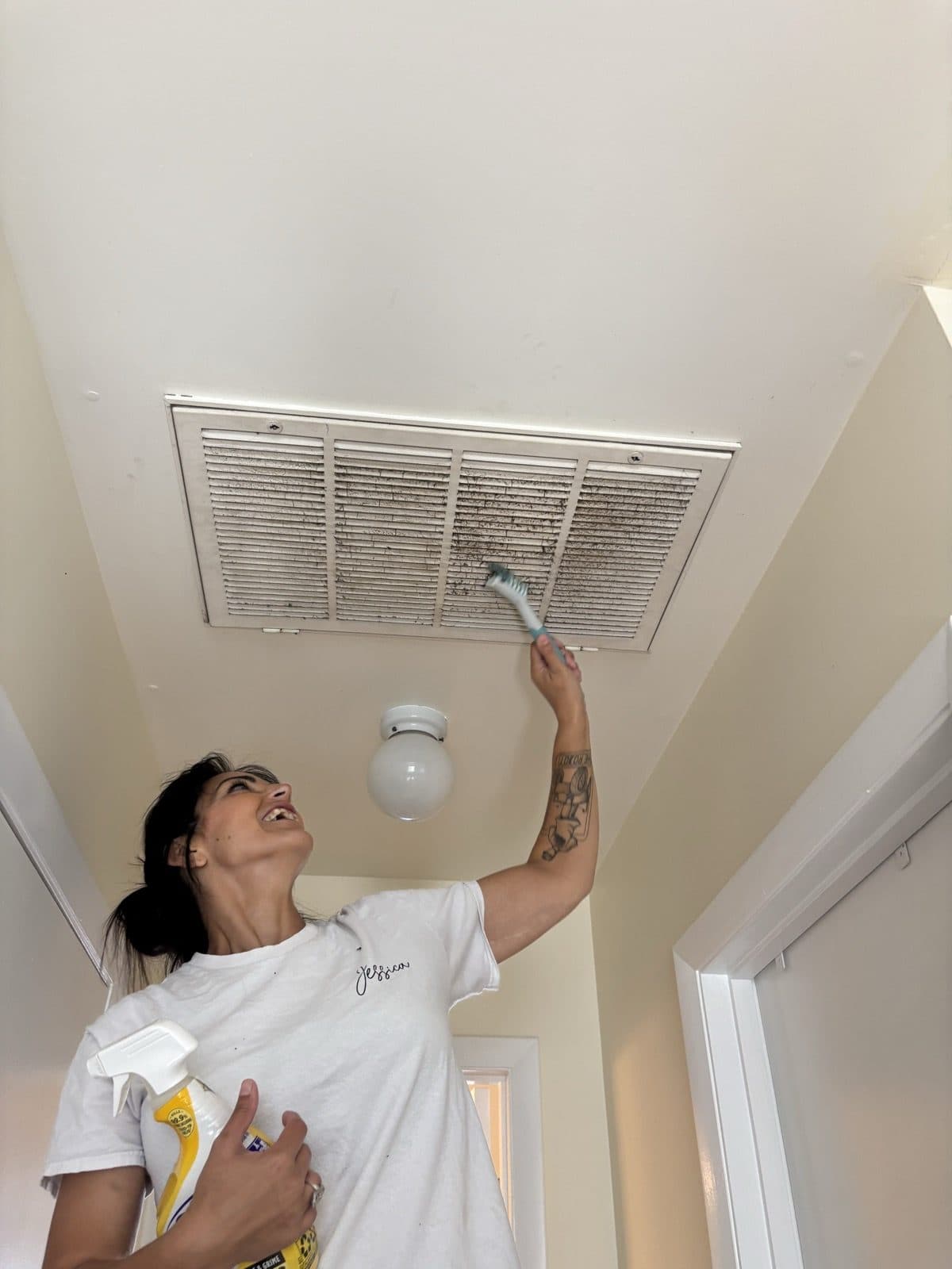 Jessica cleaning a ceiling vent during a deep clean